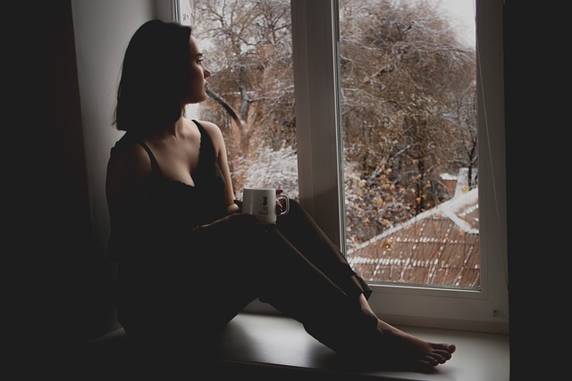 Femme en hiver, devant une fenêtre